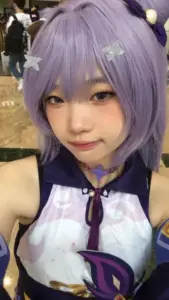 Cosplayer collei cầm cung xanh đứng giữa rừng cây, biểu cảm hơi ngại tạo cảm giác gần gũi