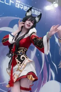 Nữ coser hóa thân Ahri K/DA trong outfit đen lấp lánh, tóc hồng dài và dáng pose sân khấu