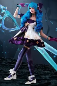 Cô gái tóc vàng cosplay Janna, cầm trượng gió và đứng nhẹ nhàng giữa phông nền xanh nhạt