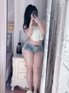 Gương soi ghi lại mỹ nhân áo trắng quần denim cầm điện thoại che mặt trong phòng