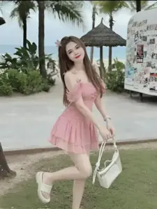 Sát bãi biển xanh cô gái mặc váy hồng xòe bước đi với nụ cười tươi