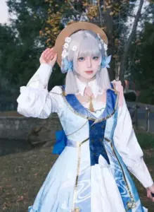 Cosplayer furina mặc váy xanh trắng ngồi trên ghế cổ điển, ánh mắt kiêu kỳ rất hợp phong cách Fontaine