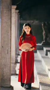 Thiếu nữ áo dài đỏ cầm mâm nhỏ, phong cách áo dài nổi bật trước cánh cửa xưa
