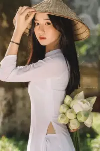 Cô gái áo dài nhung xanh ngồi cạnh rèm đỏ, tóc uốn nhẹ và thần thái sang mềm