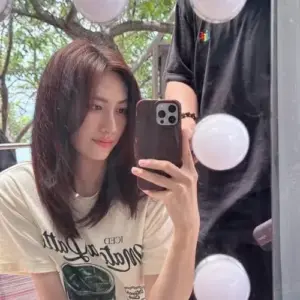 Tấm selfie gương ghi lại mái tóc dài, áo phông trắng và ánh đèn tròn lung linh