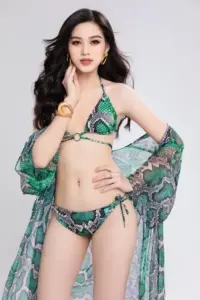 Trong khung hình nền xám, người mẫu mặc bikini xanh lá khoác khăn mỏng, tóc xoăn bồng