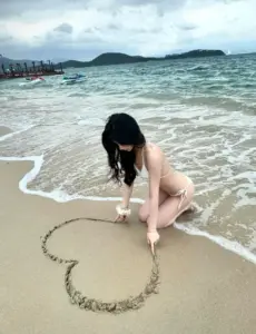 Giữa bãi cát ướt, dáng ngồi cúi đầu tạo hình trái tim, bikini sáng màu nhìn rất mềm