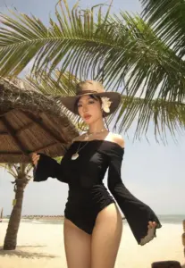 Dưới tán dừa, người đẹp mặc bikini liền thân tay dài đen tạo dáng tự tin trước ống kính