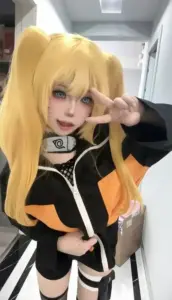 Cô nàng mặc áo ninja cam tạo dáng tự tin bên bức tường xám trong concept Naruto năng động