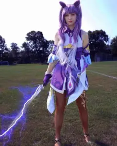 Cosplayer kokomi tóc hồng xanh ngồi cạnh hồ nước, outfit pastel làm nổi bật vẻ thiếu nữ xinh đẹp