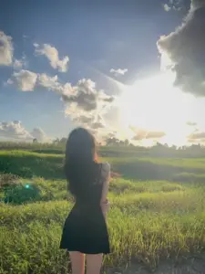 Cô gái che mặt đứng giữa đồng cỏ hoàng hôn, váy đen thành bóng dáng mềm mại