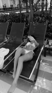 Ghế tắm nắng dài, cô gái mặc bikini đen nằm thư giãn trong khung hình đen trắng