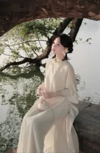 Bóng cây ven nước ôm dáng nàng áo dài kem ngồi nghiêng trong ánh sáng rất mềm