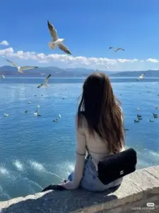 Cô gái đội mũ rộng vành đứng nhìn biển, dáng sau lưng mang cảm giác rất tự do