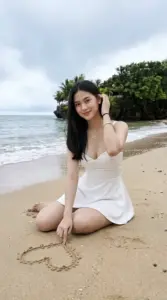Bãi cát trắng và hàng cây xanh ôm lấy dáng quỳ trong outfit trắng dịu mắt