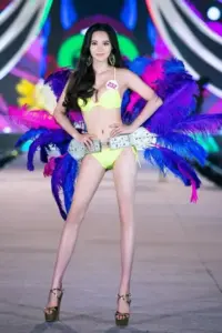 Trong khung sân khấu tím xanh, nàng bikini vàng chanh tạo dáng với đôi cánh lớn