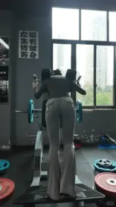 Khung cửa phòng gym hắt sáng lên cô gái mặc quần xám, tư thế đứng khỏe và tự tin