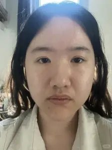 Khuôn mặt mộc nhìn gần trong áo trắng, ánh sáng phẳng làm ảnh có vibe mặt tỉnh queo