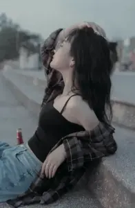 Thiếu nữ mặc áo hai dây đen ngồi bên đường với nhà sáng tạo nội dung nét buồn nhẹ