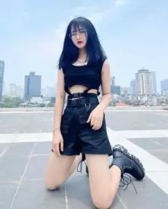 Thiếu nữ áo đen ngồi trên sân thượng giữa nền trời xanh khoe dáng nhỏ nhắn tự tin