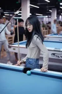 Cô gái áo trắng đứng bên bàn bida với mái tóc dài đen và dáng người nhỏ nhắn