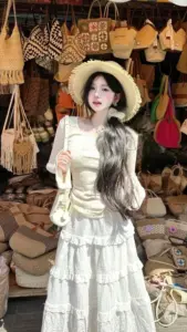 Cô gái mặc váy trắng xếp tầng đứng giữa gian đồ thủ công, nụ cười đầy duyên