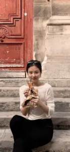 Khoảnh khắc ngồi trên bậc đá cho thấy cô gái áo sáng ôm thú bông, tóc buộc gọn