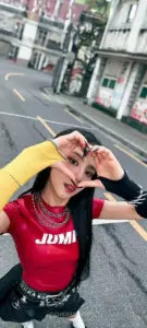 Trên phố nắng, cô gái đội mũ trắng tạo dáng trái tim với áo đỏ nổi bật