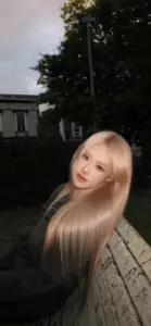 Bên lan can tối màu, nữ idol tóc vàng nhìn thẳng máy ảnh, áo sáng giúp gương mặt thêm trong trẻo