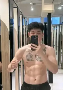 Chàng trai tập gym selfie trước gương, khẩu trang đen, hình xăm và cơ bụng rõ nét