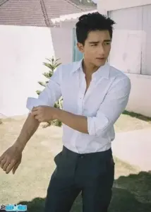 Chàng trai áo sơ mi trắng xắn tay, đứng dưới nắng với vẻ mặt nghiêm và tóc vuốt gọn