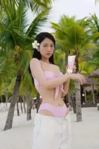 Sau hàng cọ xanh, dáng đứng trong bikini tím nhạt cầm điện thoại tạo vẻ tự nhiên