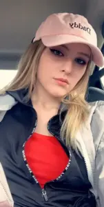 Selfie trong xe cho thấy cô gái đội mũ hồng, áo đỏ dưới áo khoác xanh đậm