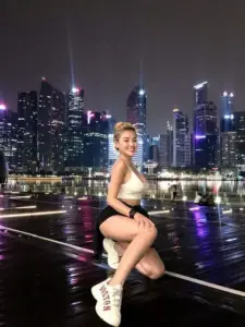 Phía thành phố đêm, Ngân 98 ngồi tạo dáng bên lan can với outfit trắng đen năng động