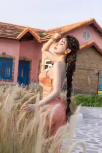 Giữa khu nghỉ dưỡng, cô gái quay nhẹ khoe mái tóc xoăn cùng outfit hồng trắng mềm mại