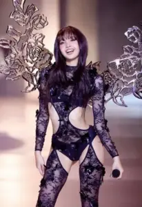 Người mẫu tóc mái diện bodysuit ren đen, tạo dáng lạnh nhẹ trước phông nền hồng tím