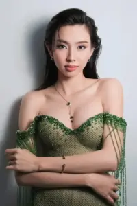 Trong ảnh chân dung, cô nàng khoanh tay với áo xanh lá, tóc đen buộc cao gọn