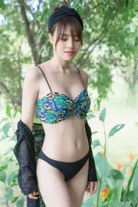 Giữa mảng cây xanh, cô gái mặc bikini hoa, tóc mái nhẹ và khoác áo đen hờ hững