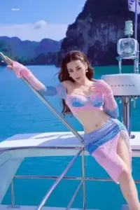 Trên du thuyền, cô mặc bikini pastel và váy lưới, tay vịn lan can nhìn xa