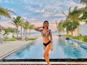 Giữa hồ vô cực cô gái bikini đen vàng bước đi tự tin, phía sau là hàng dừa