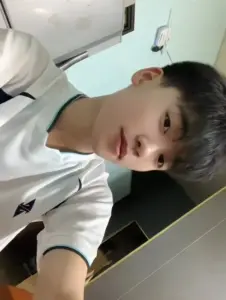 Cậu bạn áo trắng chụp selfie góc nghiêng, tóc cắt ngắn và biểu cảm tinh nghịch trong lớp