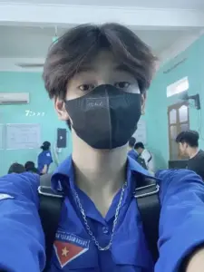Ảnh chàng trai Việt đeo khẩu trang trong lớp học, áo xanh nổi bật dưới ánh sáng lạnh