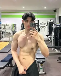 Gương mặt trẻ khoe cơ bụng săn chắc trước gương phòng gym, quần short đen đơn giản