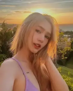 Ánh hoàng hôn phủ lên mái tóc vàng của cô gái mặc áo tím, tạo nét visual búp bê mềm mại