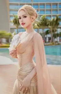 Cô gái tóc vàng mặc váy voan màu be đứng bên hồ bơi, dáng nghiêng nhẹ nhàng và thanh lịch